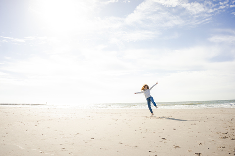 Glückliche Frau, die am Strand Spaß hat und im Sand tanzt, lizenzfreies Stockfoto