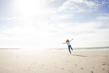 Happy woman having fun at the beach, dancing in the sand - KNSF04246