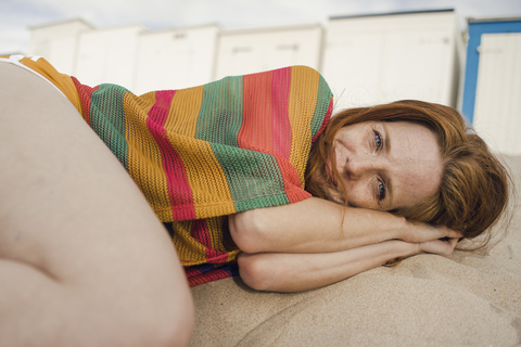 Redheaded woman resting in sand on the beach stock photo