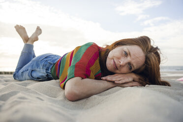 Redheaded woman lying in sand on the beach - KNSF04267