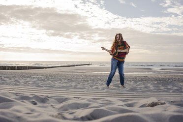 Happy woman having fun at the beach, dancing in the sand - KNSF04269