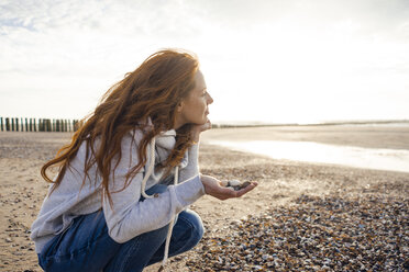 Redheaded woman collecting shell on the beach - KNSF04273