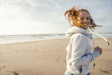 Redheaded woman running on the beach, laughing - KNSF04274