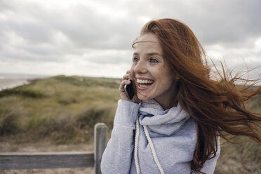 Rothaarige Frau benutzt Smartphone am Strand - KNSF04281