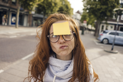 Rothaarige Frau mit Haftnotiz auf der Stirn, lizenzfreies Stockfoto