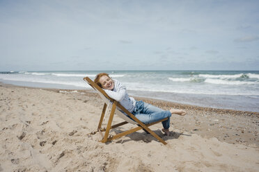Smiling woman lying in deck chair, enjoying sunbath at the beach - KNSF04302