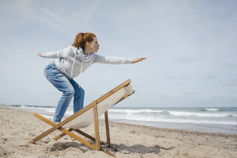 Woman standing on deck chair, pretending to surf stock photo