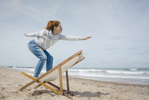 Woman standing on deck chair, pretending to surf - KNSF04303