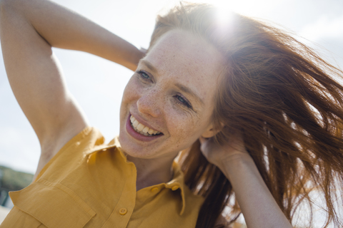 Porträt einer rothaarigen Frau, die fröhlich am Strand lacht, lizenzfreies Stockfoto