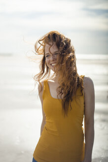 Porträt einer rothaarigen Frau, die fröhlich am Strand lacht - KNSF04310