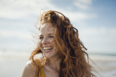 Porträt einer rothaarigen Frau, die fröhlich am Strand lacht - KNSF04311