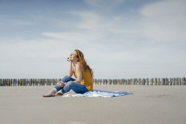 Woman sitting on the beach, enjoying the sun - KNSF04314