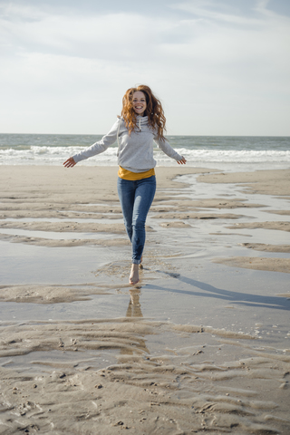 Glückliche Frau, die sich am Strand amüsiert, läuft am Meer, lizenzfreies Stockfoto