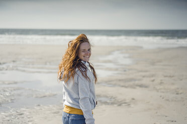 Rothaarige Frau entspannt sich am Strand und lacht - KNSF04320