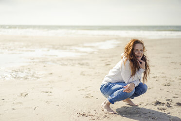 Rothaarige Frau entspannt sich am Strand, hockend - KNSF04323