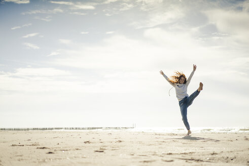 Happy woman having fun at the beach, dancing in the sand - KNSF04326