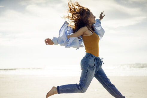 Happy woman having fun at the beach, jumping in the air - KNSF04327