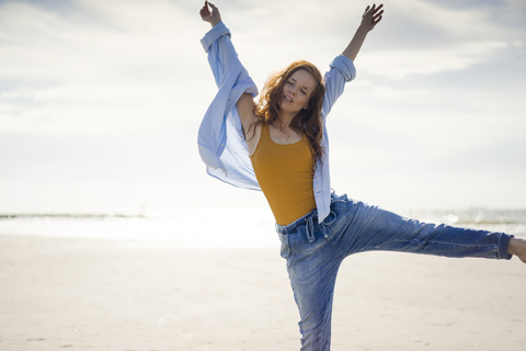 Glückliche Frau, die am Strand Spaß hat und in die Luft springt, lizenzfreies Stockfoto