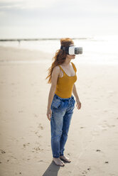 Rothaarige Frau mit VR-Brille am Strand - KNSF04329