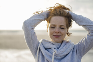 Redheaded woman enjoying fresh air at the beach - KNSF04336