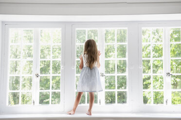 A child standing at a window looking out. - MINF01767