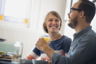 Ein Paar sitzt in einem Café und unterhält sich lächelnd bei einer Tasse Kaffee. - MINF01835