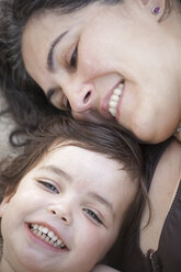 Nahaufnahme einer Mutter und einer Tochter, die lächelnd und lachend die Köpfe zusammenstecken. - MINF01842
