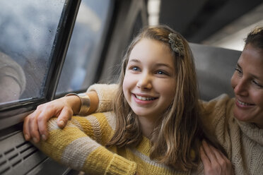 Ein Mann und ein junges Mädchen sitzen in einem Zugwaggon am Fenster und blicken auf die Landschaft. Sie lächeln aufgeregt. - MINF01844