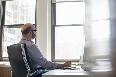 Office life. A man sitting at a desk using a computer, looking intently at the screen. - MINF01911