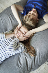 A family home. A boy and girl lying on the sofa with their heads close together. View from above. - MINF01976