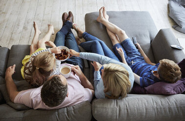 A family at home. View from above of two adults and two children seated on a sofa together. - MINF01998