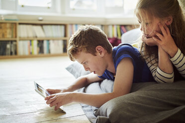 Zwei Kinder sitzen gemeinsam an einem digitalen Tablet und schauen auf den Bildschirm. - MINF02060