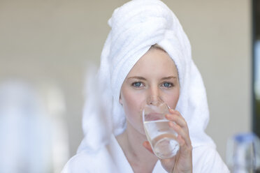 Junge Frau mit Handtuch auf dem Kopf trinkt Wasser - ISF17007