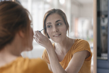 Frau trägt vor einem Spiegel Wimperntusche auf - JOSF02288
