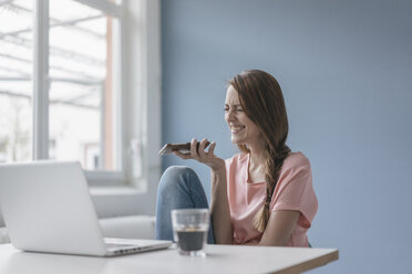 Frau zu Hause am Schreibtisch sitzend, mit Laptop und Smartphone - JOSF02310