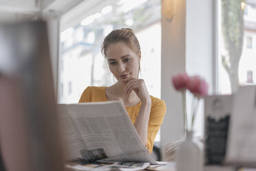 Junge Frau sitzt im Coworking Space und liest Zeitung - JOSF02319