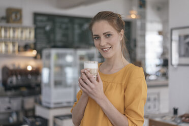 Junge Unternehmerin steht in ihrem Café und trinkt Kaffee - JOSF02325