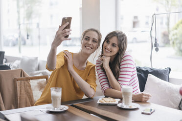 Two girlfriends meeting in a coffee shop, taking selfie - JOSF02336
