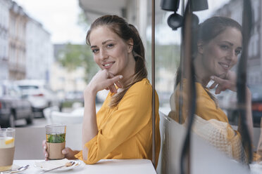 Woman sitting in coffee shop, drinking peppermint tea - JOSF02341