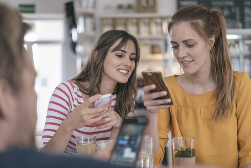 Zwei Freundinnen treffen sich in einem Café und benutzen Smartphones - JOSF02342