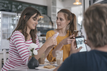 Zwei Freundinnen treffen sich in einem Café und benutzen Smartphones - JOSF02343