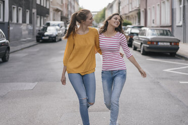Zwei Freundinnen, die sich in der Stadt amüsieren und Arm in Arm gehen - JOSF02398