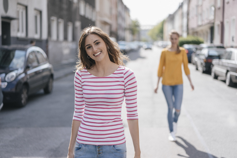 Frau geht auf der Straße, gefolgt von einem Freund, lizenzfreies Stockfoto