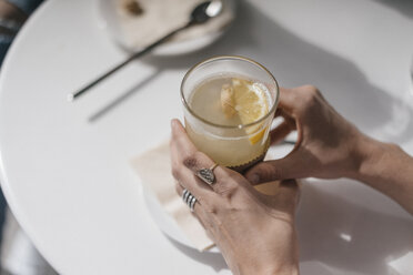 Woman holding glass of ginger lemon tea - JOSF02407