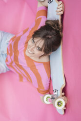 Frau hält Skateboard und schaut nach oben - JOSF02426