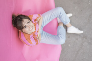 Selbstbewusste junge Frau sitzt auf rosa Hintergrund - JOSF02428
