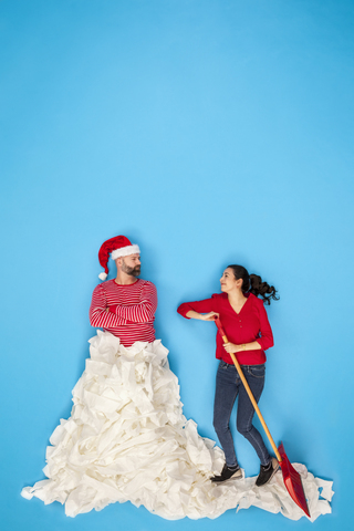 Ehepaar beim Schneeschaufeln, Mann mit Weihnachtsmannmütze, lizenzfreies Stockfoto
