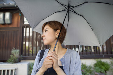 Woman standing outdoors, holding an umbrella. - MINF02261