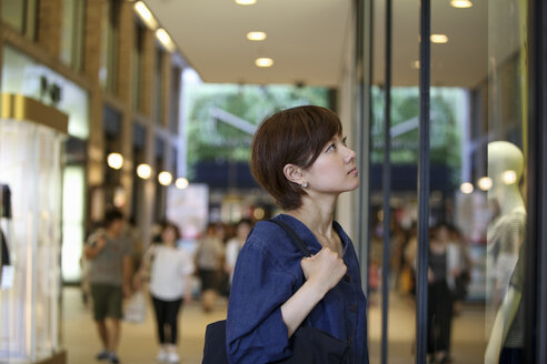 Eine Frau in einem Einkaufszentrum betrachtet eine Schaufensterauslage. - MINF02269