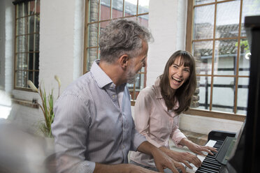 Mature couple having fun at home, playing the piano - FKF03068